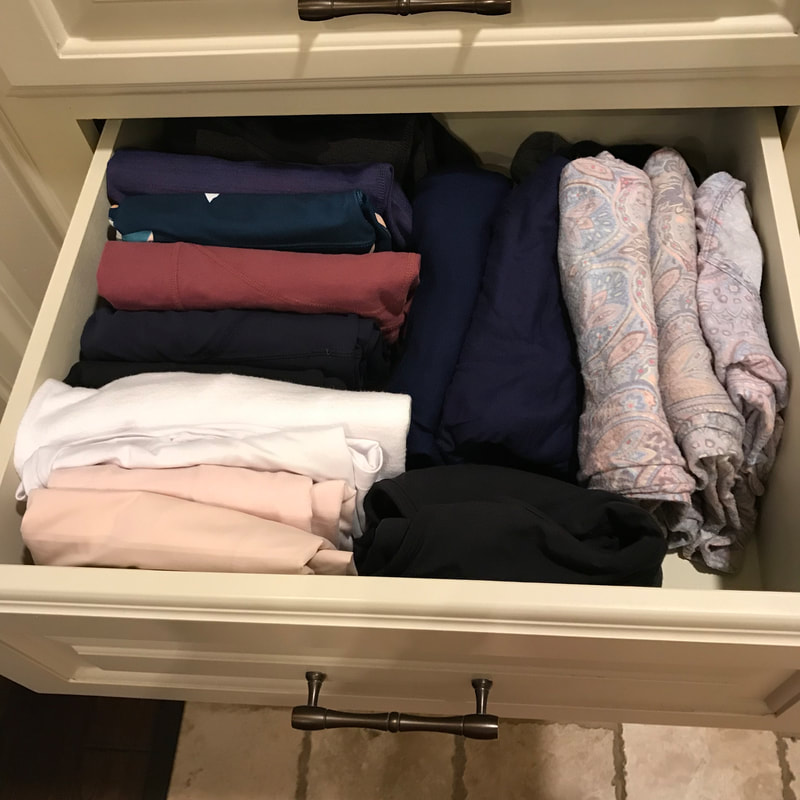 Open drawer with folded bathing suits of various colors, folded and organized vertically