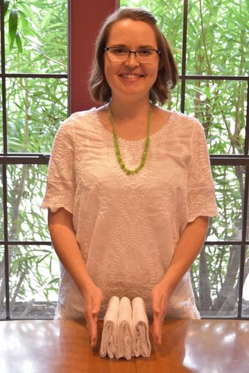 Laura Sinclair Professional Home Organizer of Flourish Organizing with three shirts folded using the KonMari Method