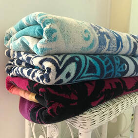 Three colorful towels folded on white wicker stand