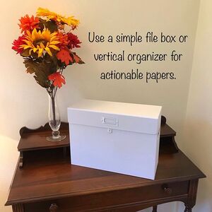 Dark wood antique writing desk with closed white file box with lid, a vase of fall colored orange and yellow flowers, and the writing 