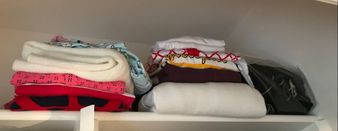 Sweaters folded on top shelf of closet