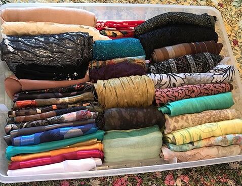 Scarves of all colors and textures neatly folded in a plastic bin, place vertically so you can see them all at once