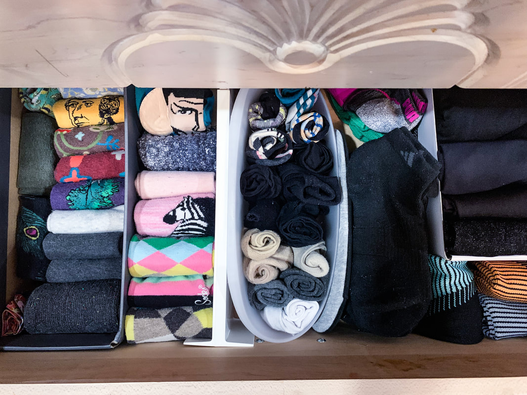Open drawer in a dresser with four rows of folded socks of various colors