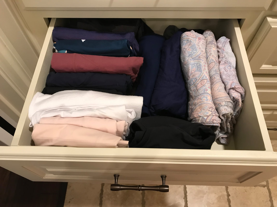 Open drawer with folded swimsuits filed vertically in the space